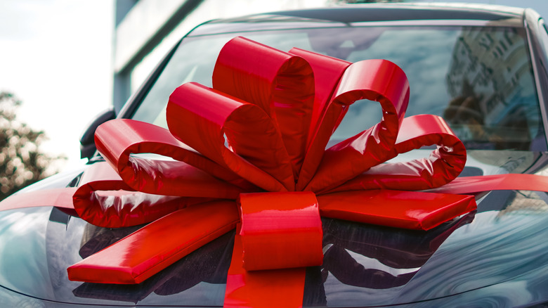 Red gift ribbon on the hood of a black car.