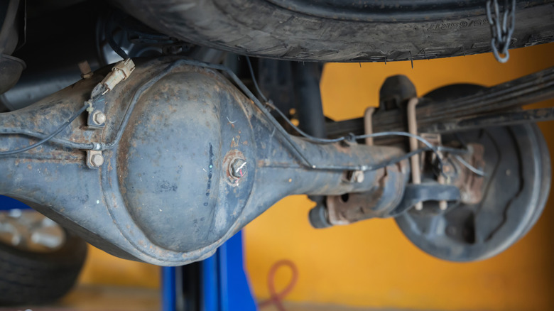 A close-up of an old car's rusty rear-axle differential.