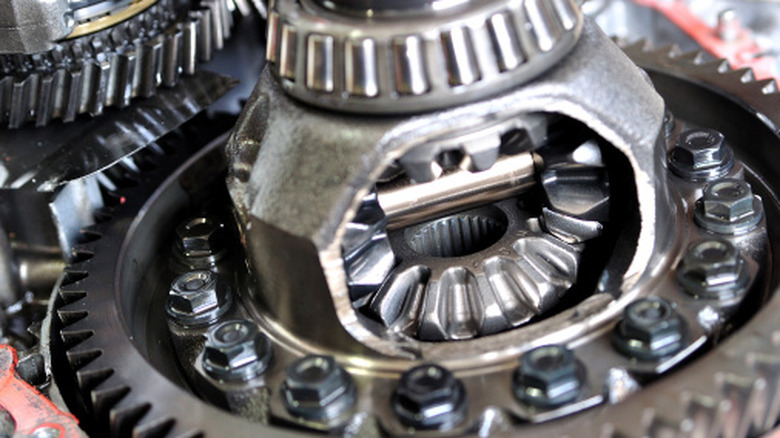 A close-up of a car's differential housing with spider gears, bolts, and a ring gear.