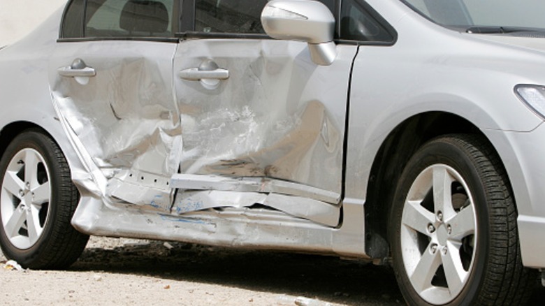 A silver sedan with a damaged side.