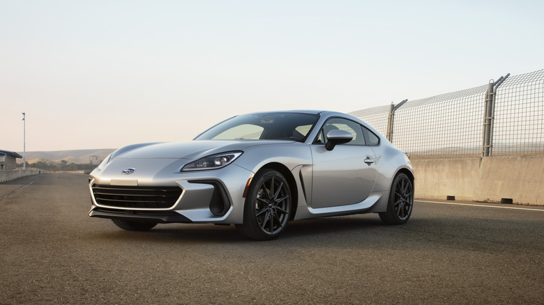 A silver 2025 Subaru BRZ in front a fence.