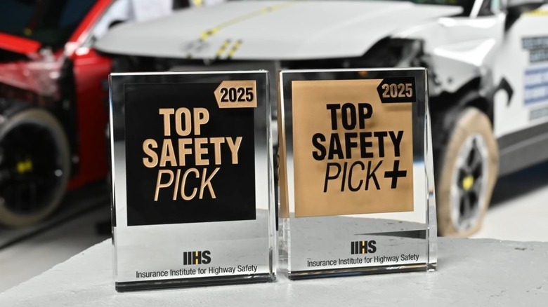 Shot of 2025 IIHS Top Safety Pick and Top Safety Pick+ awards with vehicles that have undergone crash testing in the background
