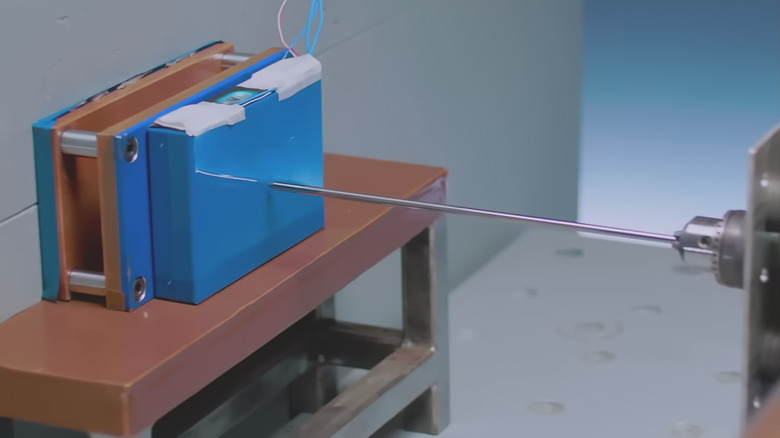 A battery cell about to be pierced with a needle as part of the nail penetration test.