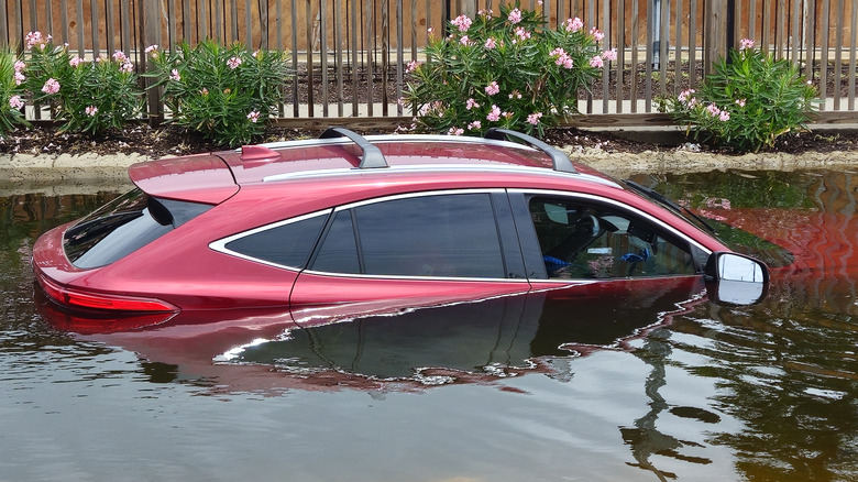 A red SUV covered by flood waters.