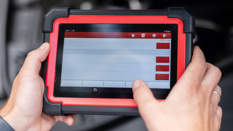 An OBD2 scanner with a blank interface being held by a person