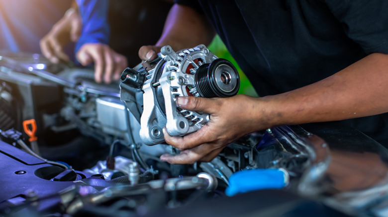 A mechanic installing an alternator.