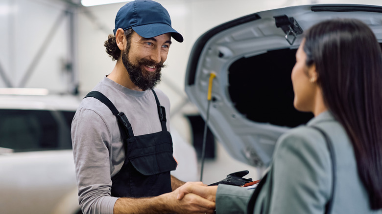 A customer and a mechanic shaking hands at the garage.