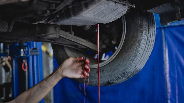 A mechanic removes the ATF drain plug to remove the old fluid.