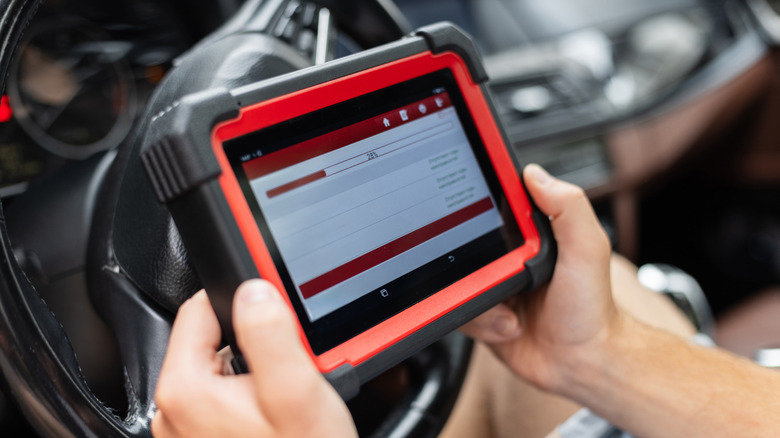 A mechanic using a scan tool to diagnose a car.