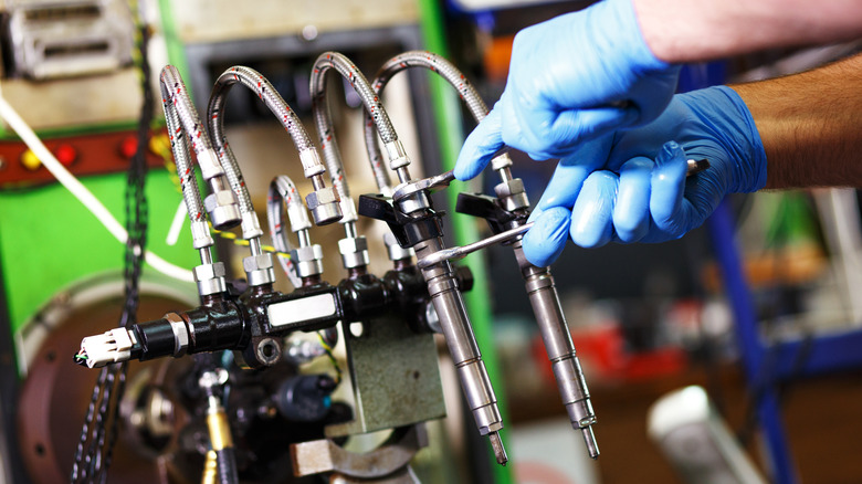Diesel injectors being tested by a person with gloves