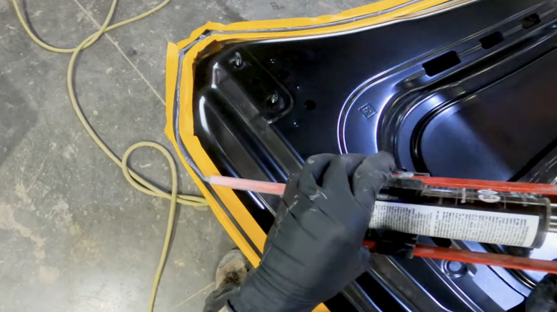 A mechanic doing manual application of seam sealer