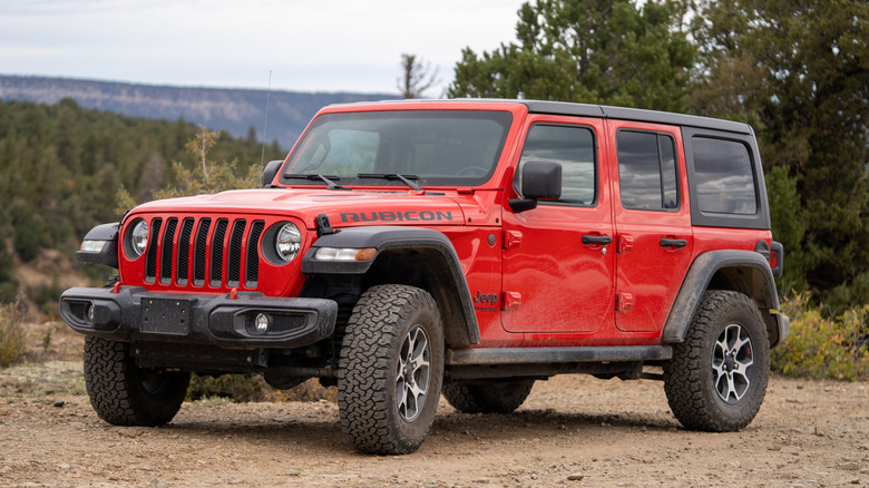 Red Jeep Wrangler parked on a dirt road.
