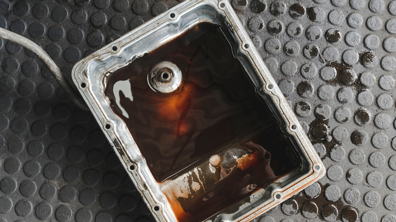 Old and contaminated ATF leftovers in the transmission oil pan of a car