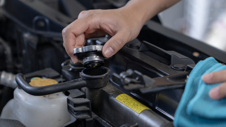 A car owner opening the radiator cap to check the coolant level