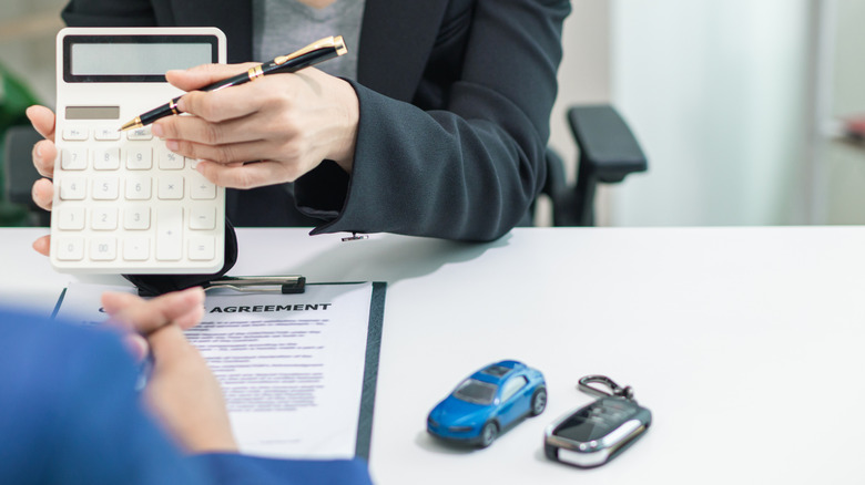 A dealership salesperson going over car purchase details with a customer