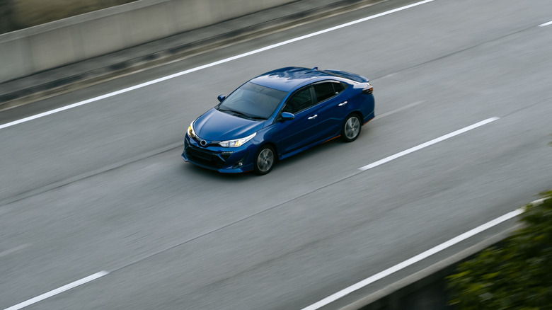 Blue sedan driving on empty highway