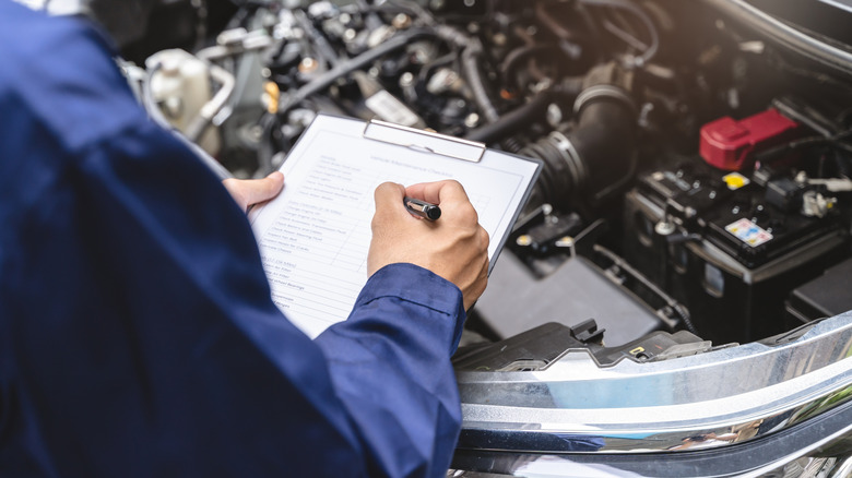 A mechanic drafting a written, itemized inspection and repair quote for a customer.