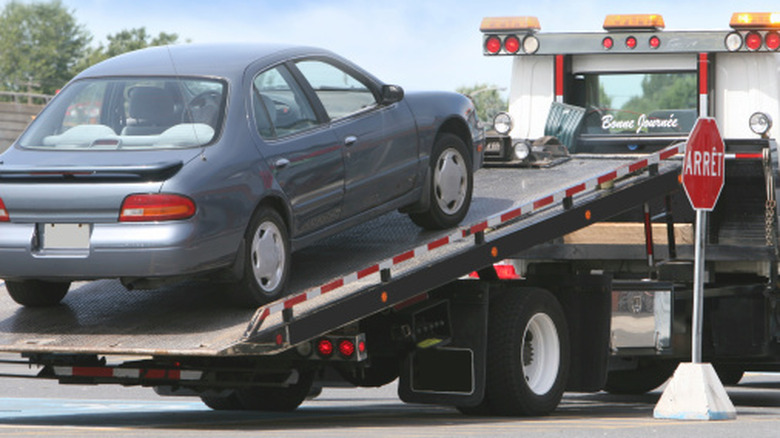 A compact sedan on the back of a tow truck