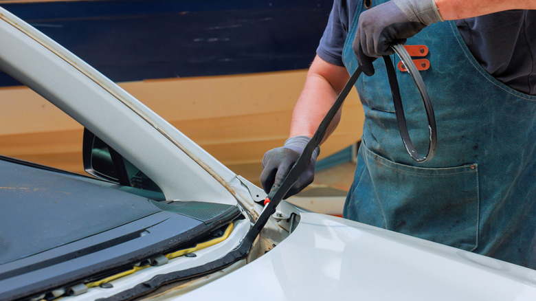 A technician removing an old rubber seal from a windshield frame