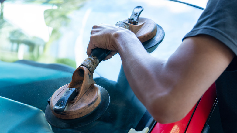 A technician using suction tools to install new windshield glass