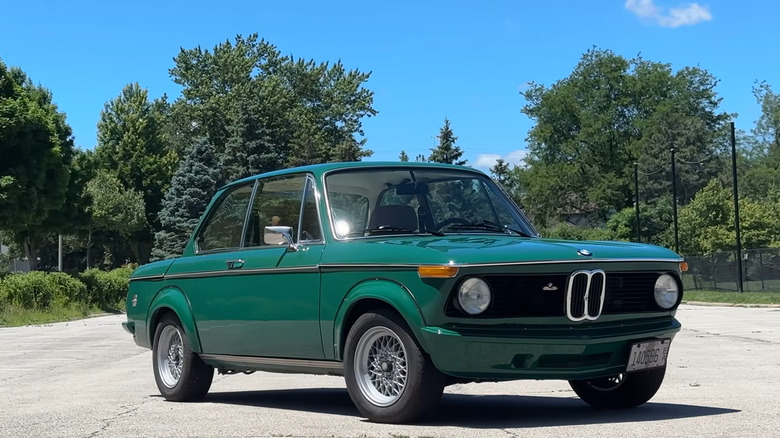 A front-right 3/4 shot of a green BMW 2002 on a sunny day