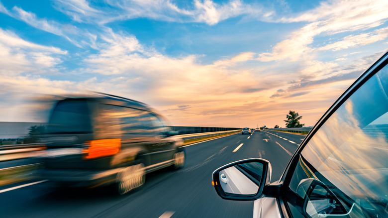 A blurred shot of two cars traveling side by side on the highway.