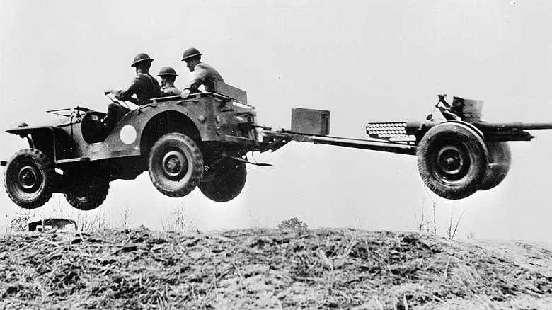A side shot of a Bantam Jeep flying over a jump