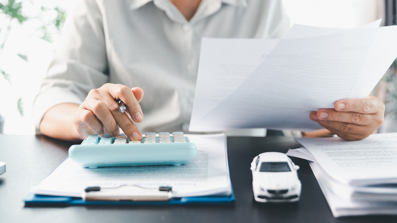 An insurance agent works on a car insurance policy using a calculator