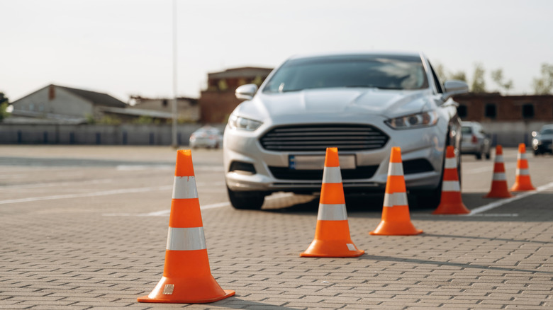 A Ford Fusion drives past a set of cones at a driving school