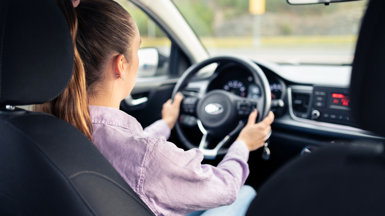 A woman drives a car during the daytime