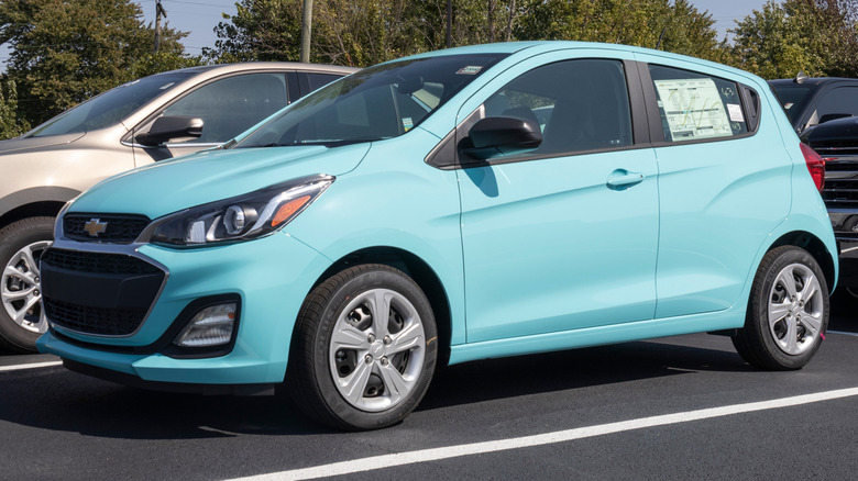 Teal Chevrolet Spark sitting on a dealership lot.
