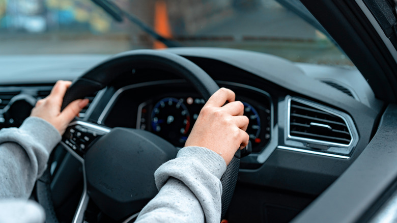 A person keeping both hands on the steering wheel while driving.
