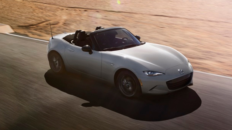 A 2024 Mazda MX-5 Miata with its roof down driving on a road