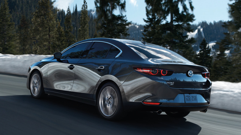 A rear 3/4 view of a 2020 Mazda3 sedan on a road with snow nearby