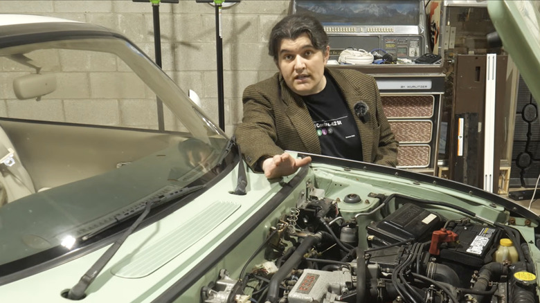 YouTube host leaning over and engine bay describing car computers