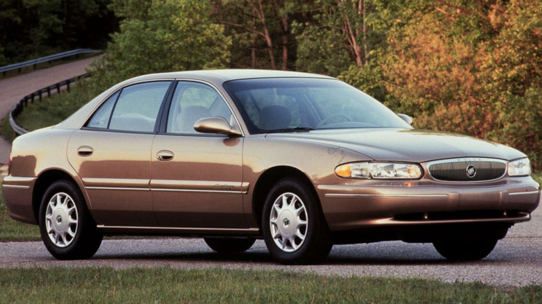 A 2000 Buick Century parked on a sunny road with trees in the background