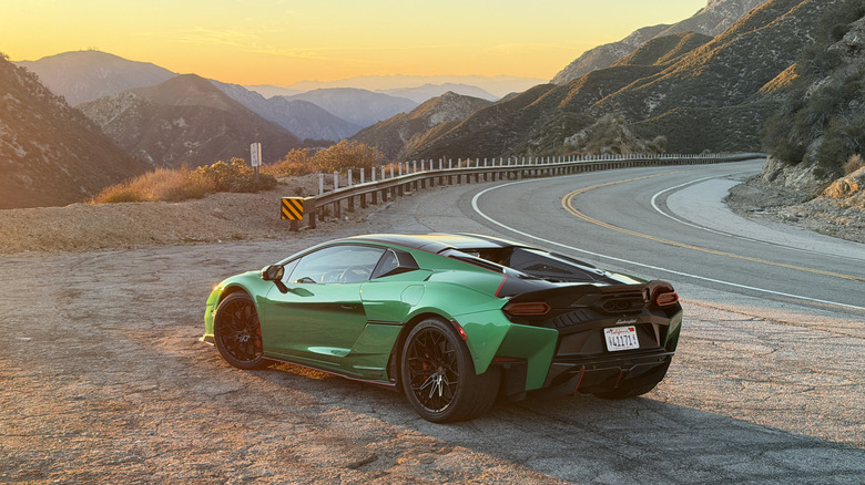 Rear 3/4 view of a green Lamborghini Temerario in front of a beautiful mountain sunset