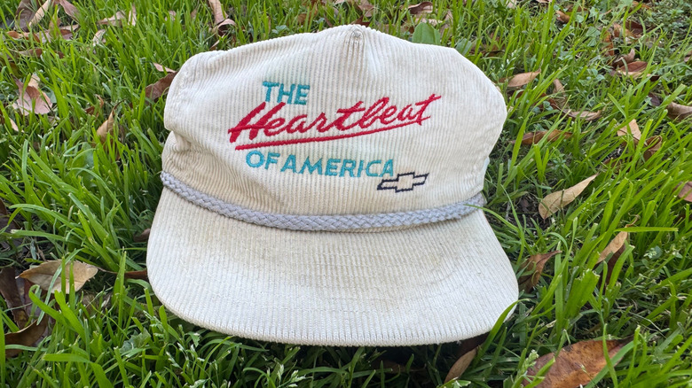 My vintage white corduroy Heartbeat Of America hat sitting on green grass with brown leaves