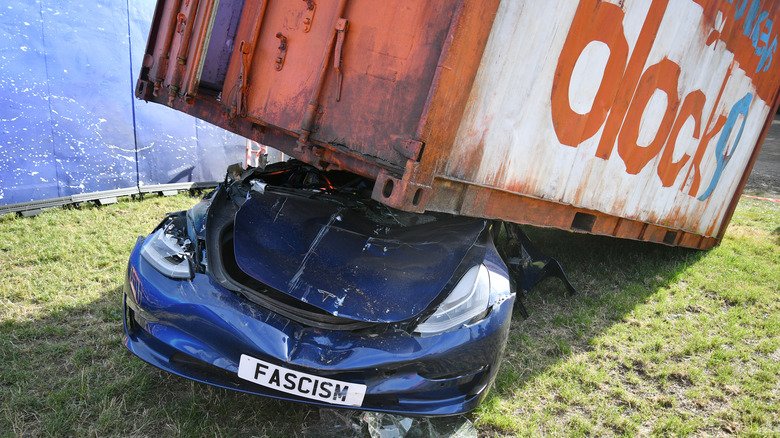 A crushed Tesla car with a registration plate that reads 'Fascism' is presented as part of a political art installation during day two of Glastonbury festival 2025 at Worthy Farm, Pilton on June 26, 2025 in Glastonbury, England. Established by Michael Eavis in 1970, Glastonbury has grown into the UK's largest music festival, drawing over 200,000 fans to enjoy performances across more than 100 stages. In 2026, the festival will take a fallow year, a planned pause to allow the Worthy Farm site time to rest and recover.