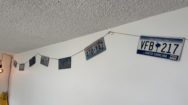 A photo of my license plate collection hanging on a white wall with plates from Washington, South Carolina, Nevada, and California