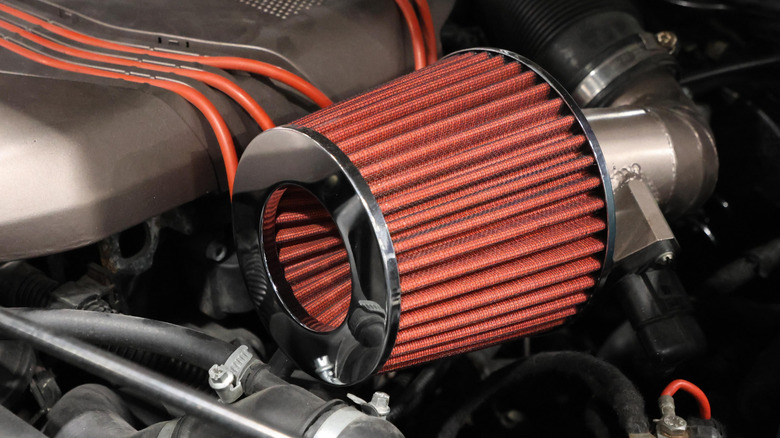 A short ram intake with a red cone filter under the hood of a car