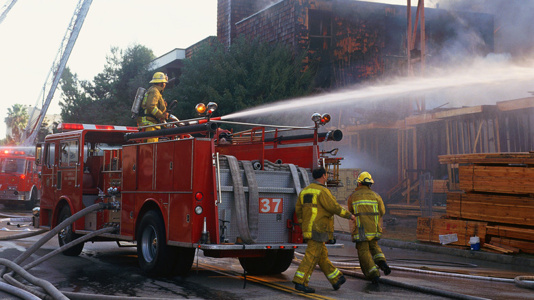 A fire engine and firefighters putting out a fire by spraying water