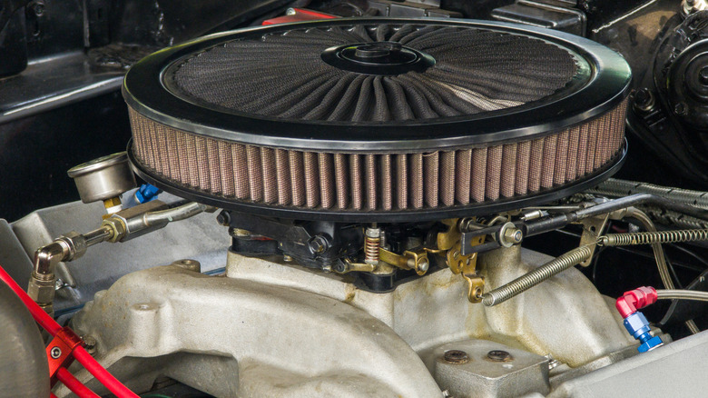 A close up view of a carbureted V-8 engine with a performance air filter on top