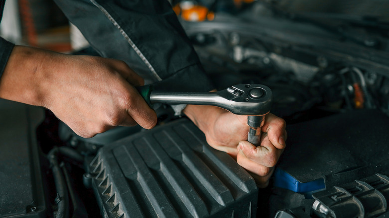 Close up of mechanic working on a car engine with ratchet