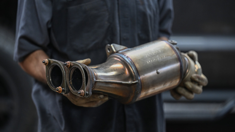 A mechanic holding a catalytic converter
