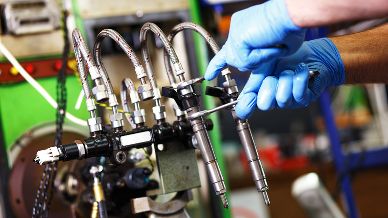 A professional mechanic testing a diesel injector in a workshop.