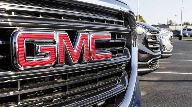 The grill and reddish GMC badge connected a GMC Sierra Denali parked adjacent to different GMC vehicles connected a trader lot