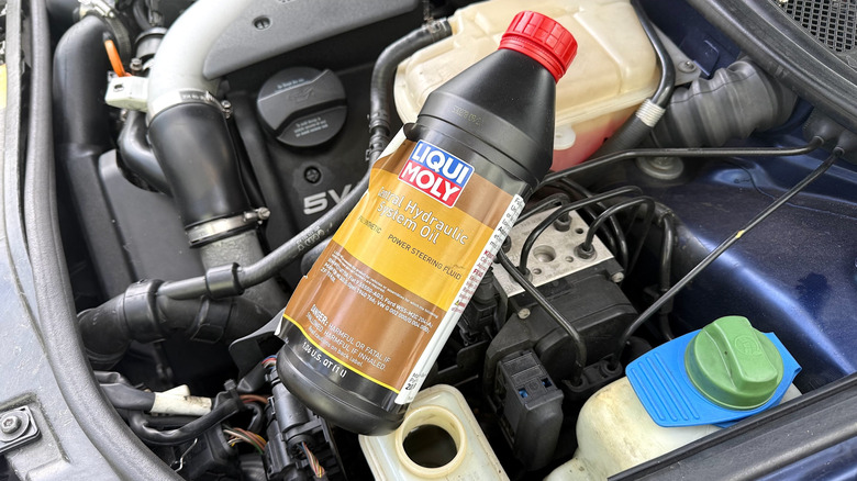 A bottle of power steering oil sitting in a B5-generation Audi S4's engine bay.