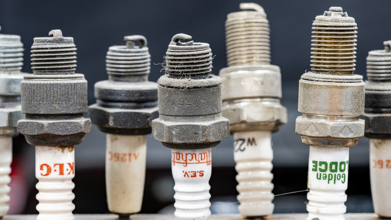 A collection of old spark plugs lined up at a shop table