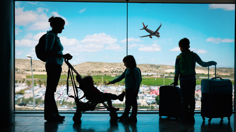 A young family is silhouetted against a large airport window